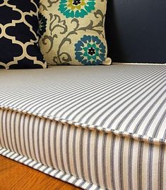 a bed with blue and white pillows on top of it next to a wooden floor