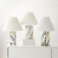 three marble lamps sitting on top of a white table next to each other and a lamp shade