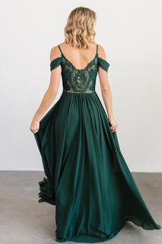 a woman in a long green dress is looking back at the camera and she has her hands on her hips