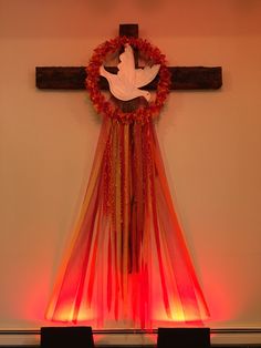 a cross with a wreath on top of it and some lights around it in the corner