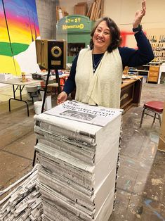 a woman standing next to stacks of newspapers