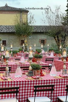 an outdoor dining area with red and white checkered tablecloths, candles and flowers