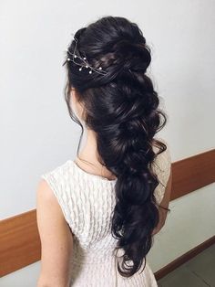 a woman with long black hair wearing a white dress and some flowers in her hair