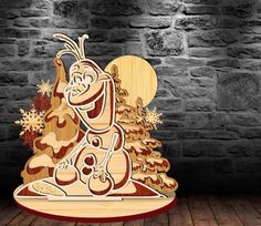 a wooden cutout of a cartoon character sitting in front of a christmas tree with snowflakes