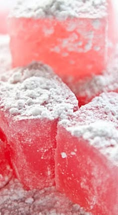 several pieces of pink and white cake with powdered sugar on top, sitting next to each other