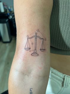 a lady with a tattoo on her arm has a libra symbol tattooed on it