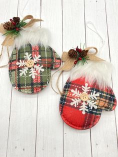 two plaid christmas mitts with snowflakes and pine cones on them sitting on a white wooden surface