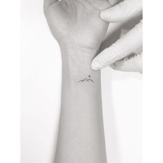 a person is holding their arm up with a small tattoo on it