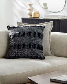 a black and white pillow sitting on top of a couch next to a coffee table