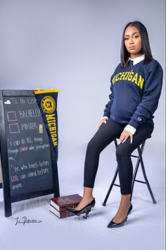 a woman sitting on top of a chair next to a chalkboard