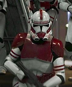 the star wars character is dressed in red and white armor, with two other characters behind him