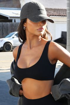 a woman in a black sports bra top and hat