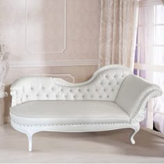 a white chaise lounge sitting in front of a window next to a wall with curtains