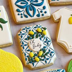 decorated cookies are arranged on a table with blue and yellow accents, including ones that say oh baby