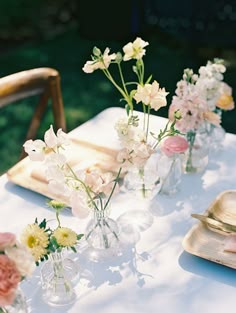 several vases filled with flowers sitting on top of a white table cloth covered table