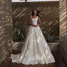 a woman in a white wedding dress standing on a brick floor next to a cactus