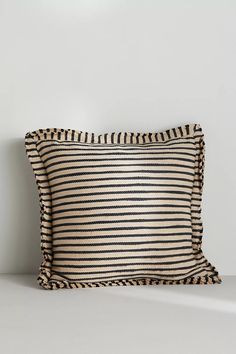 a black and white striped pillow sitting on top of a table next to a wall