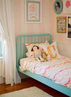 a child's bedroom with pink and white striped walls, blue bedding, and a teddy bear sitting on the pillow