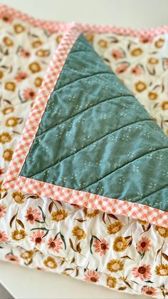 a close up of a quilted table topper on a white surface with flowers