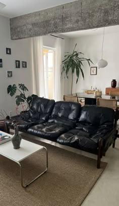 a living room with black leather couches and a coffee table in front of a window