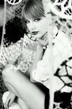 a black and white photo of a woman sitting on the ground with her hand under her chin