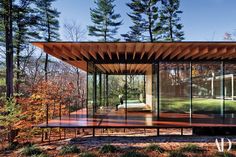 two photographs of a wooden pavilion with glass walls and wood flooring, in the woods