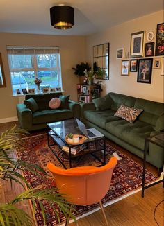 a living room with green couches and pictures on the wall above them, along with an orange coffee table