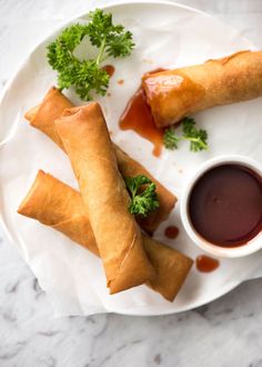 two spring rolls on a plate with dipping sauce