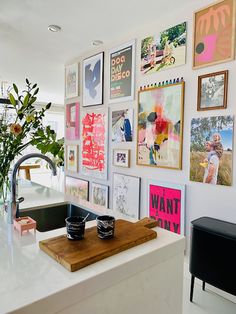 a kitchen with pictures on the wall and a wooden cutting board