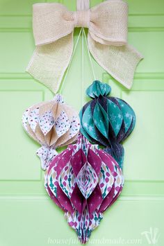 an origami heart hanging on a green door with two large bows attached to it