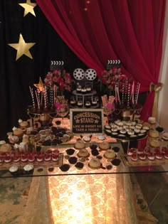 a dessert table filled with cupcakes and pastries on top of a table