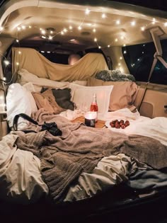 a bed in the back of a van with lights on it and blankets around it