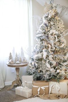 a white christmas tree with presents under it