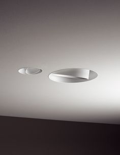 two circular lights are hanging from the ceiling in a room with white walls and black flooring