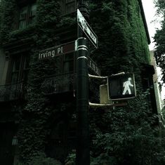 an ivy covered building with a street sign on it's corner in the foreground