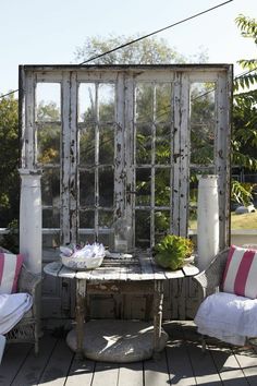 an old door is used as a screen for the outside seating area on this deck