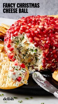 a christmas cheese ball with pomegranates and crackers on the side