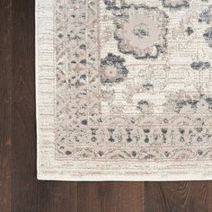 a white rug with black and grey designs on it, sitting on a wooden floor