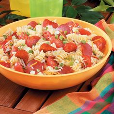 a yellow bowl filled with pasta and pepperoni on top of a colorful table cloth