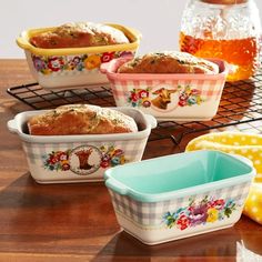 four dishes with bread in them sitting on a table next to a jar of honey