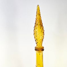 a yellow glass vase with a decorative design on the top and bottom, in front of a white background