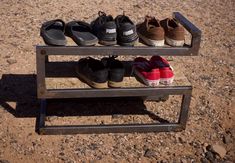 several pairs of shoes are lined up on a wooden bench in the desert, with one pair being used as a shoe rack