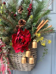 a christmas wreath hanging on the front door with bells and pine cones, evergreen branches, red poinsettis and other holiday decorations