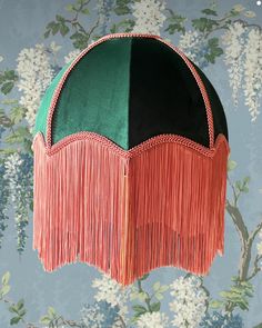 a green and red lamp hanging from the ceiling in front of wall paper with flowers on it