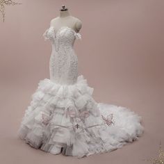 a white wedding dress is displayed on a mannequin stand in front of a pink background