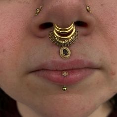 a close up of a person with gold nose rings and piercings on their nose