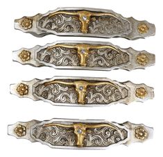 three silver and gold colored metal handles with decorative designs on each side, one has a cross in the middle