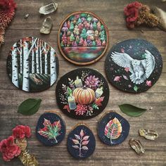 several decorated cookies sitting on top of a wooden table next to flowers and leaves in front of them