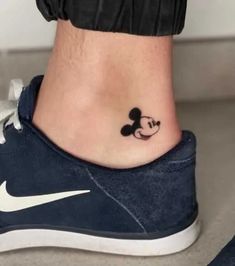 a small tattoo on the ankle of a person with a mickey mouse head in it