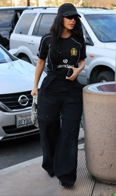 a woman is walking down the sidewalk in black